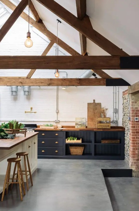 a contemporary barn kitchen with wooden beams, midnight blue cabinets with butcherblock countertops, a white kitchen island and wooden stools
