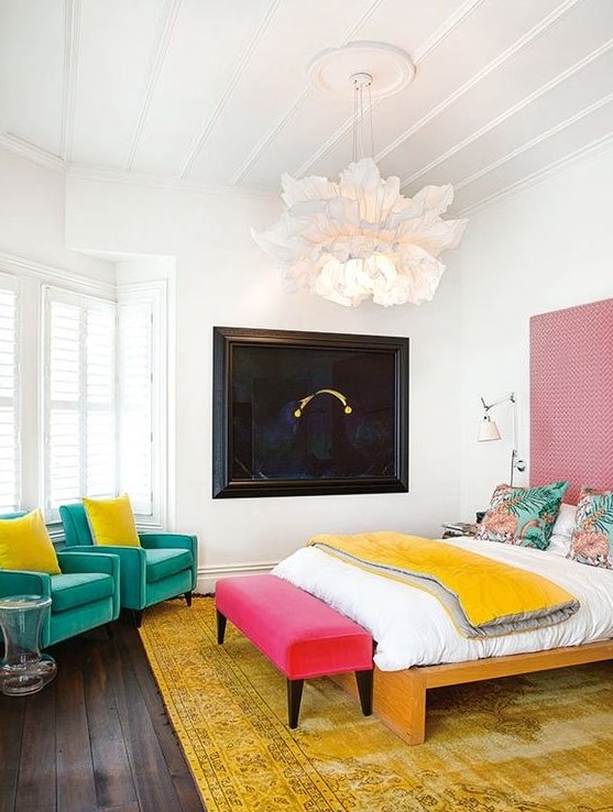 a contemporary colorful bedroom with green chairs, a pink bench, a yellow rug and blanket plus a pink wallpaper accent wall