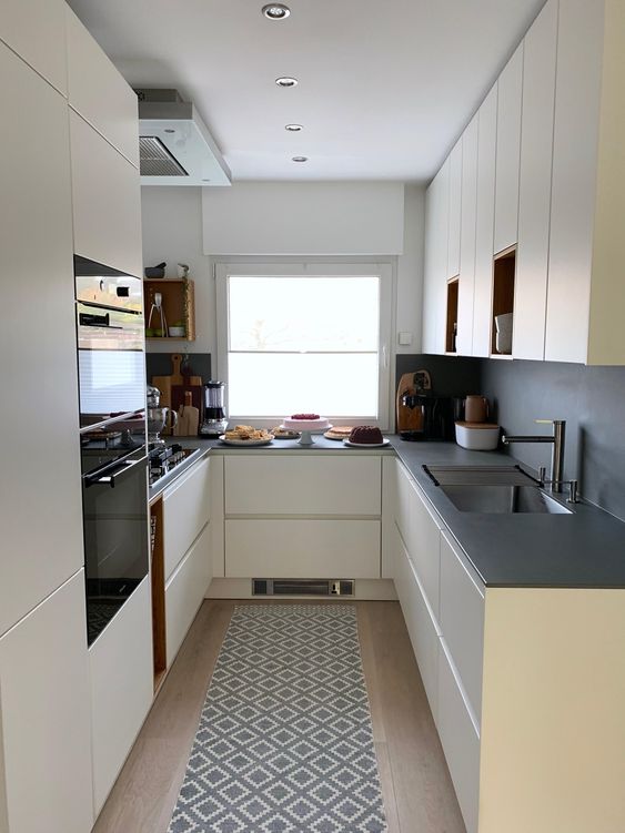 a creamy sleek kitchen with a grey backsplash and countertops, built-in appliances and a window for a view