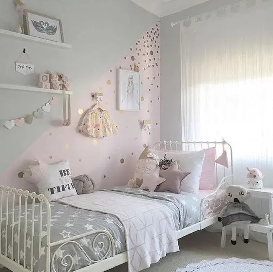 a delicate Scandinavian girl's room with ledges with artwork and toys, a white bed with mauve and grey bedding, a color block wall with polka dots