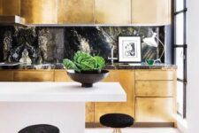 a gold kitchen with a black stone backsplash and a countertop plus a white minimalist kitchen island for a jaw-dropping look