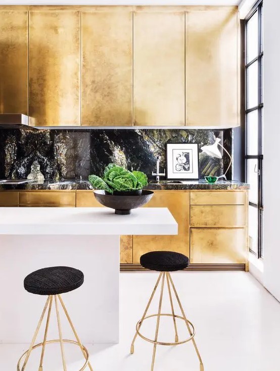 a gold kitchen with a black stone backsplash and a countertop plus a white minimalist kitchen island for a jaw-dropping look