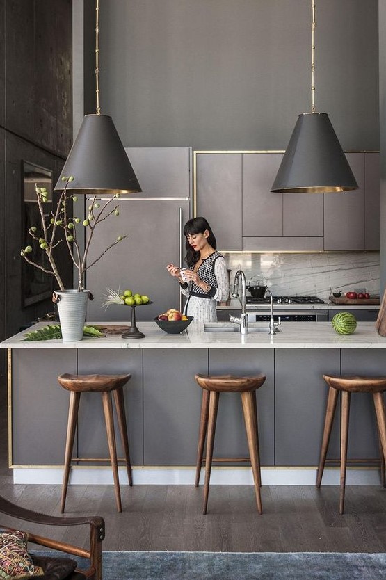 a grey contemporary kitchen with sleek lit up cabinets, pendant lamps, white stone countertops and a backsplash