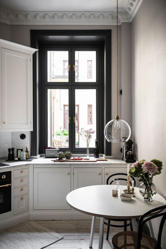 a lovely French style kitchen in black and white, with refined chairs, a round table and gilded touches