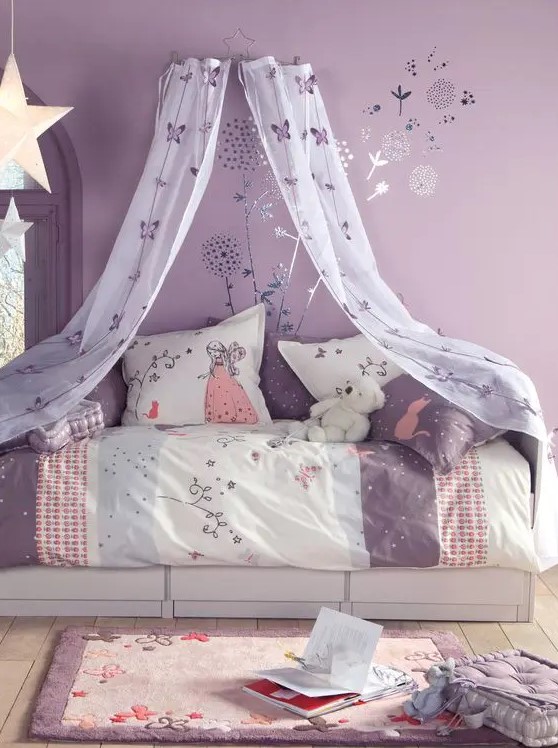a lovely purple girl's room with floral murals, a white bed with purple and neutral bedding, a cool rug and a cushion