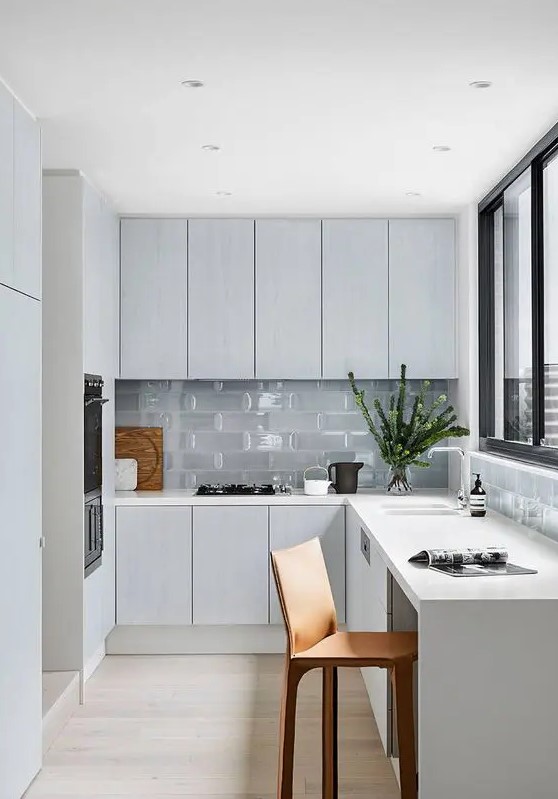 a minimal Nordic L-shaped kitchen with glass tiles and a window with a view is a lovely idea