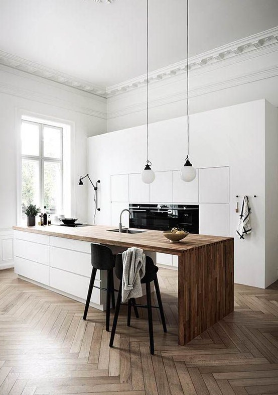 a minimalist Nordic kitchen with sleek white cabinets, a sleek white kitchen island with a wooden waterfall countertop and pendant lamps