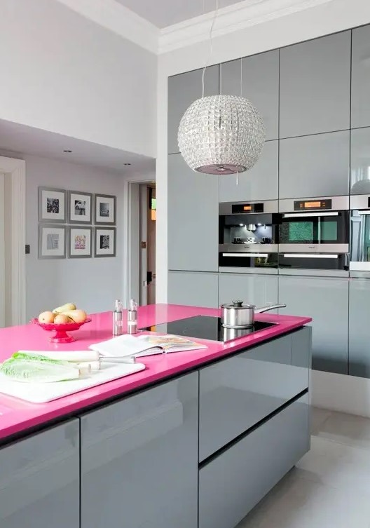 a minimalist glam kitchen done with shiny grey glossy cabinets, a hot pink kitchen island countertop and a shiny embellished pendant lamp