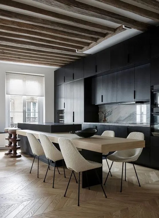 a minimalist kitchen with black cabinets, a marble backsplash, a two-part kitchen island and rough wooden beams