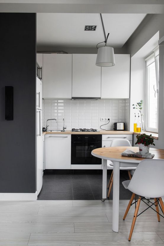 a monochromatic white kitchen with butcherblock countertops, a white tile backsplash and a round table and chairs