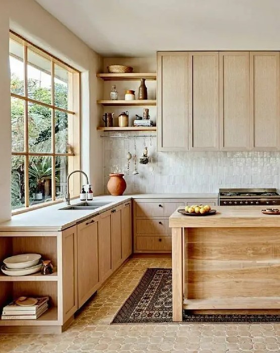 a natural-looking kitchen with light-stained cabinets, a white Zellige tile backsplash, white stone countertops, open shelves and a wooden kitchen island