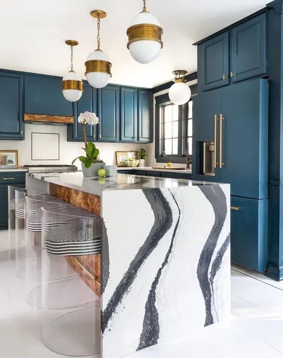 a navy kitchen with brass handles and pendant lamps, a fantastic waterfall kitchen island in black and white and striped stools