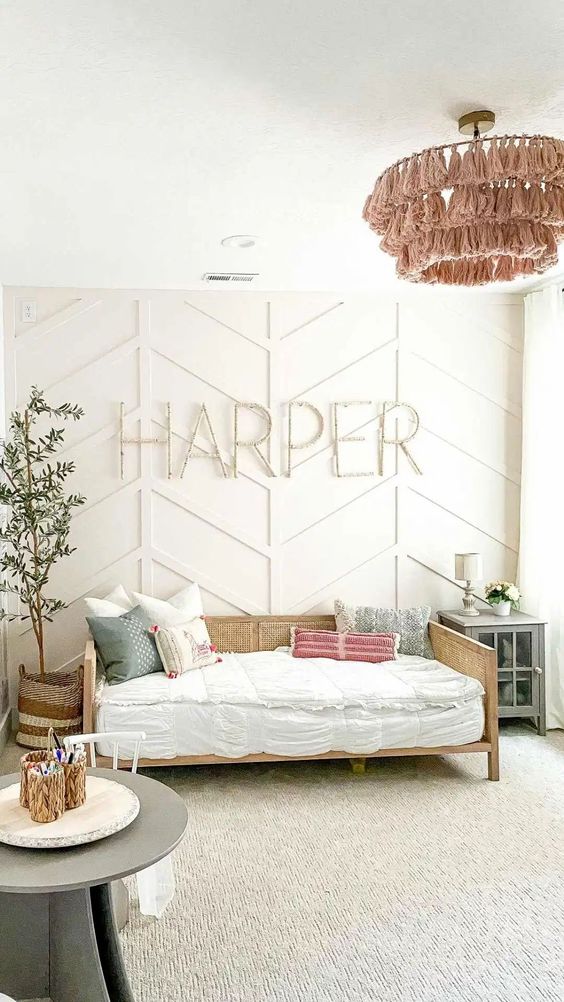 a neutral girl's room with a rattan bed, a potted tree, a grey cabinet and a grey play table with a chair