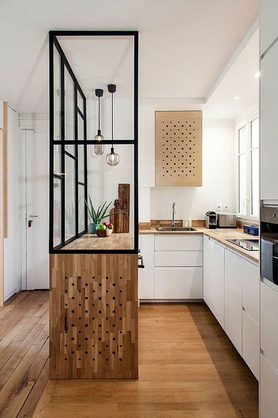 a pretty contemporary kitchen with butcherblock countertops, a kitchen island with a waterfall countertop and pendant lamps