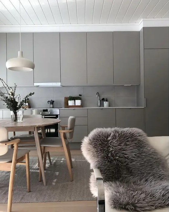 a pretty greige kitchen with sleek cabinets and a concrete tile backsplash, a neutral and cozy dining space here