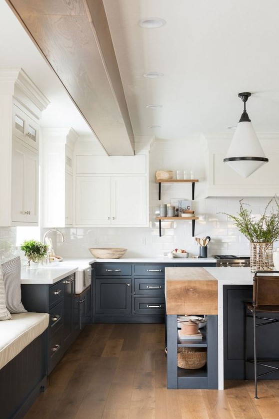 a refined two tone kitchen with navy and white shaker style cabinets, white countertops and a subway tile backsplash plus a retro pendant lamp