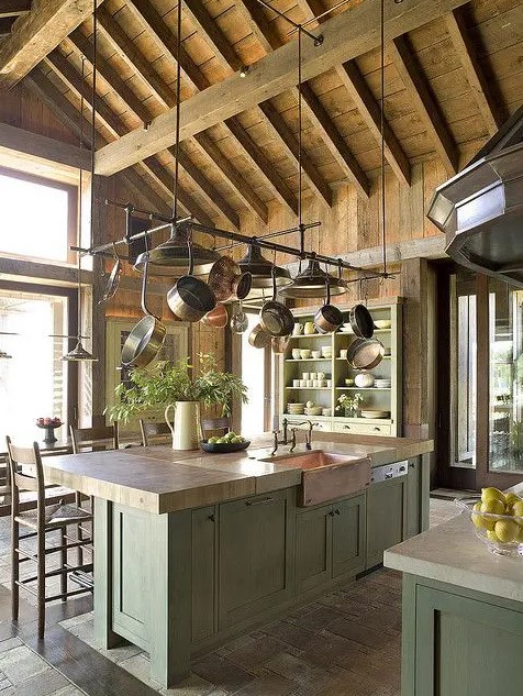 a rustic kitchen with green cabinetry, wooden and stone countertops, a wooden ceiling with beams is a chic space