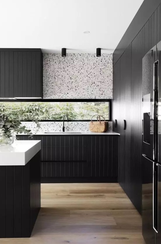 a sleek modern kitchen with black planked cabinets, a white terrazzo backsplash, white countertops and black fixtures is a lovely idea