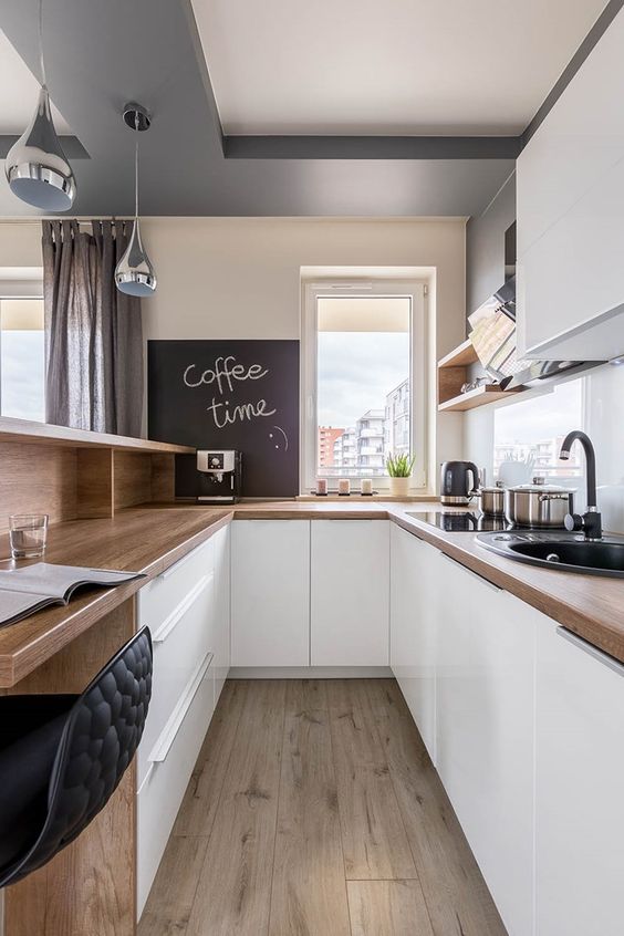 a sleek white kitchen with butcherblock countertops, open shelves and cabinets and a bar counter and workspace in one