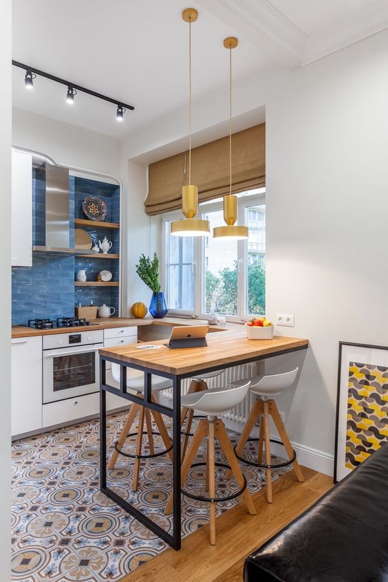a small contemporary kitchen with white cabinets, printed tiles on the floor, butcherblock countertops and a wall-mounted table