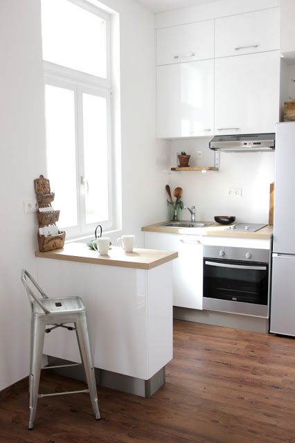 a small white kitchen with butcherblock countertops, a bar countertop that acts as a kitchen island