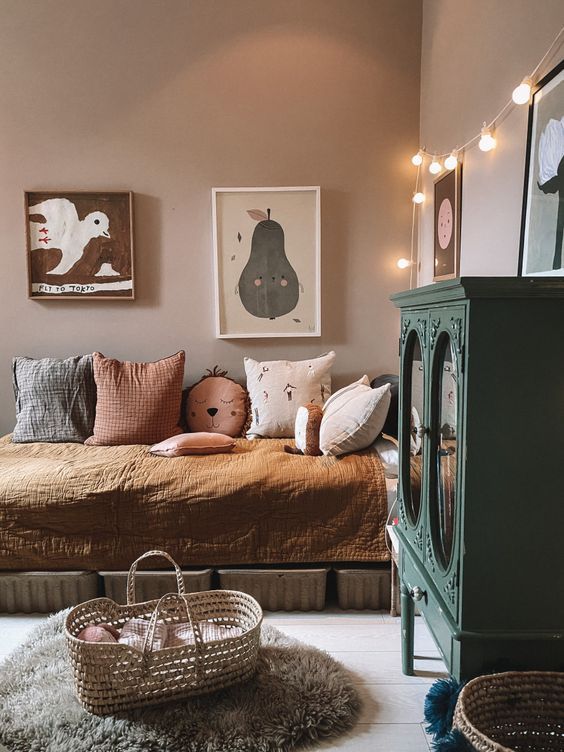 a welcoming girl's room with mauve walls, a bed with storage drawers, a dark green cabinet, a basjet and artwork