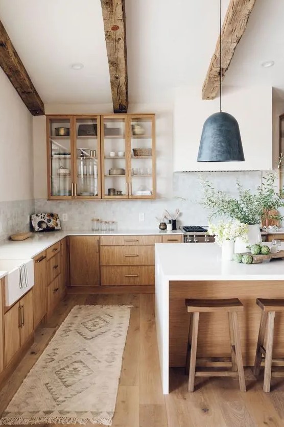 a welcoming modern farmhouse kitchen with light-colored cabinets, wooden beams and stools that warm up the space