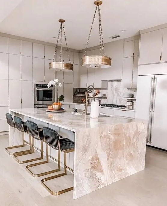 an elegant dove grey kitchen with a pink stone kitchen island, whimsy black and gold stools and gold pendant lamps