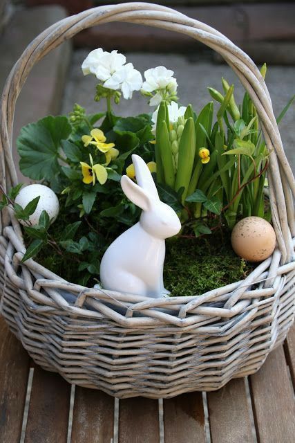 a basket with moss, spring blooms, faux eggs and a bunny is a cool decoration for both indoors and outdoors