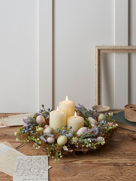a beautiful Easter centerpiece of a nest with faux blue and lilac blooms and berries plus pastel eggs and candles