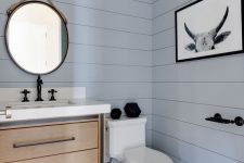 a beautiful contemporary light blue powder room, a wooden vanity, hex tiles on the floor and a mirror hanging on rope