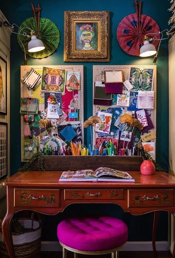 a boho maximalist home office with a navy accent wall, a vintage desk, a hot pink stool, a gallery wall and memo boards plus lights
