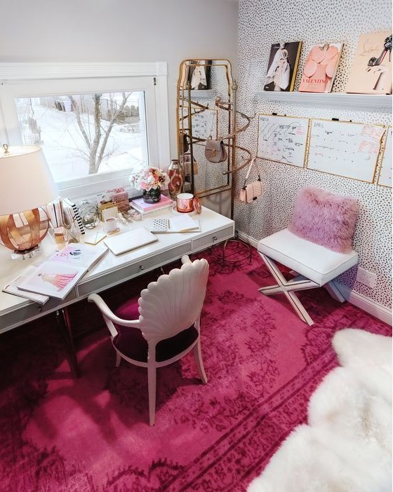 a bold feminine home office with a refined plum chair, a hot pink rug and pillow, a cool gallery wall and touches of gold