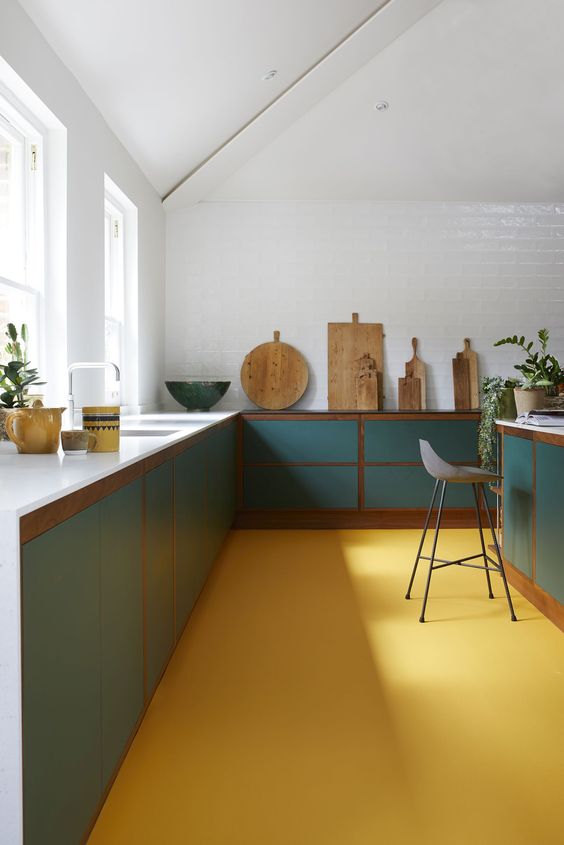 a bold kitchen with a yellow floor, green cabinets and white countertops is a very chic and cool space with a modern feel