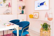 a bright home office with light pink walls, navy chairs, a colorful gallery wall and a rug, potted greenery