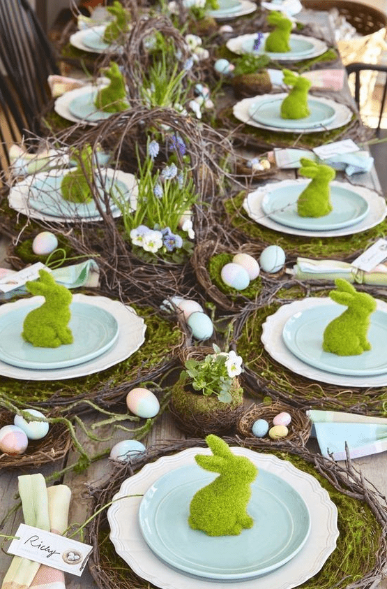 a bright rustic Easter table setting with vine placemats and moss, faux nests with colorful eggs, a vine centerpiece with blooms
