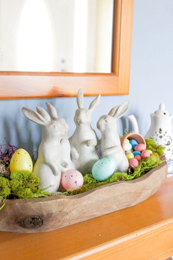 a colorful Easter decoration of a wooden bowl with colorful eggs and moss and some bunnies is great for mantels and consoles