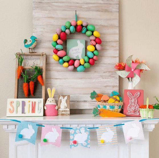 a colorful and fun Easter mantel with a bright egg wreath, a bunny bunting, a string art piece, some bunnies and a carrot garland