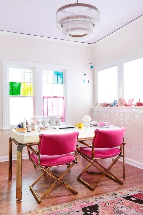 a colorful feminine home office with hot pink chairs, an elegant desk and bright touches