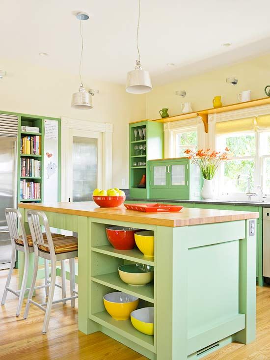 a colorful green kitchen with a matching kitchen island, butcherblock countertops, red and yellow accessories and touches