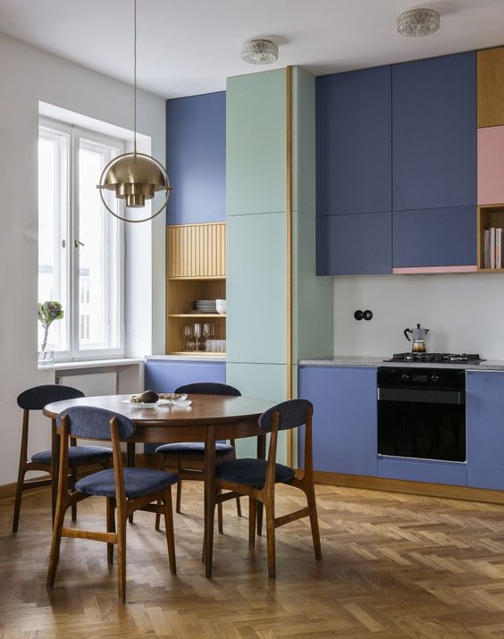 a contemporary kitchen with bold purple sleek cabinets, bright pink and yellow touches and purple chairs plus a gold pendant lamp