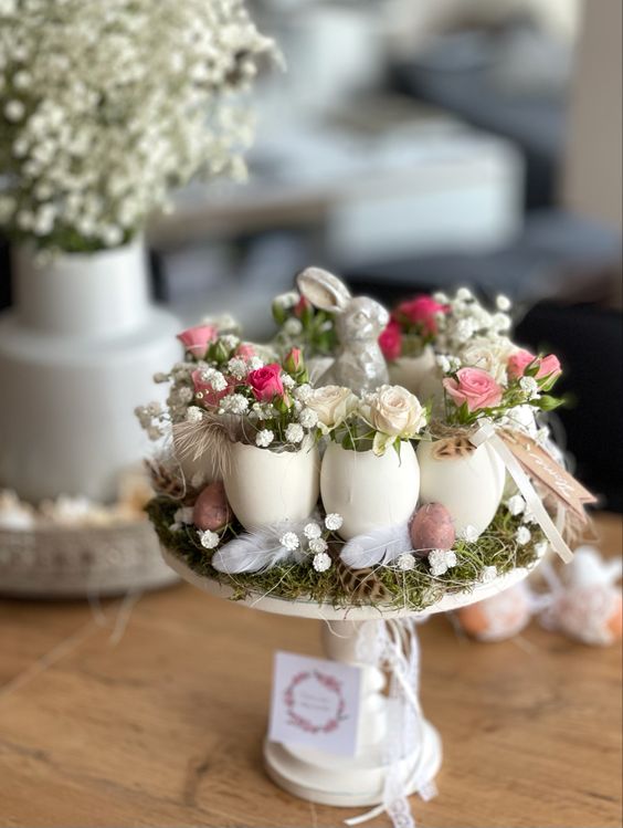 a creative Easter centerpiece with grass, feathers, baby's breath, egg shellfs with dried blooms and a small bunny
