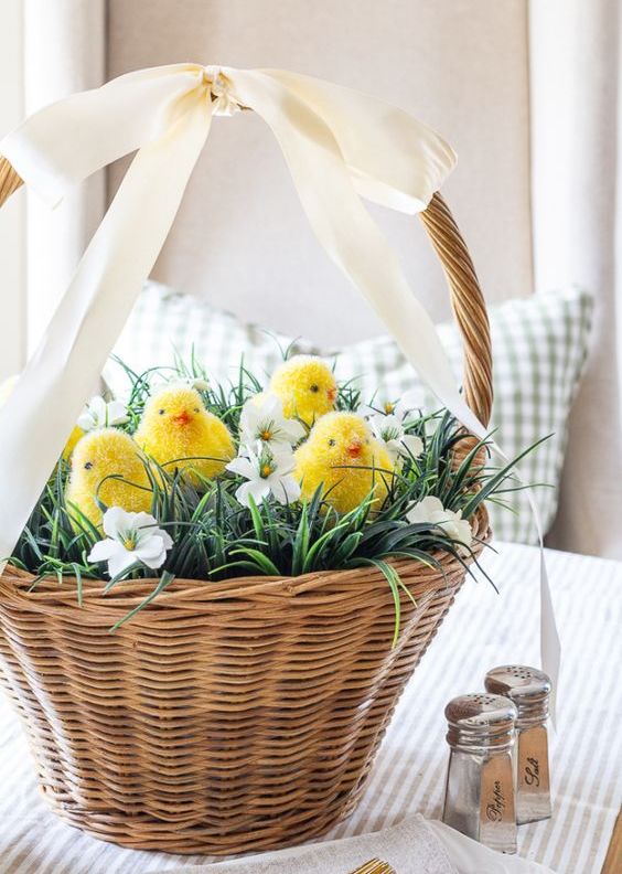 a cute rustic Easter centerpiece of a baske with faux grass, blooms and little chicks is an amazing idea to realize