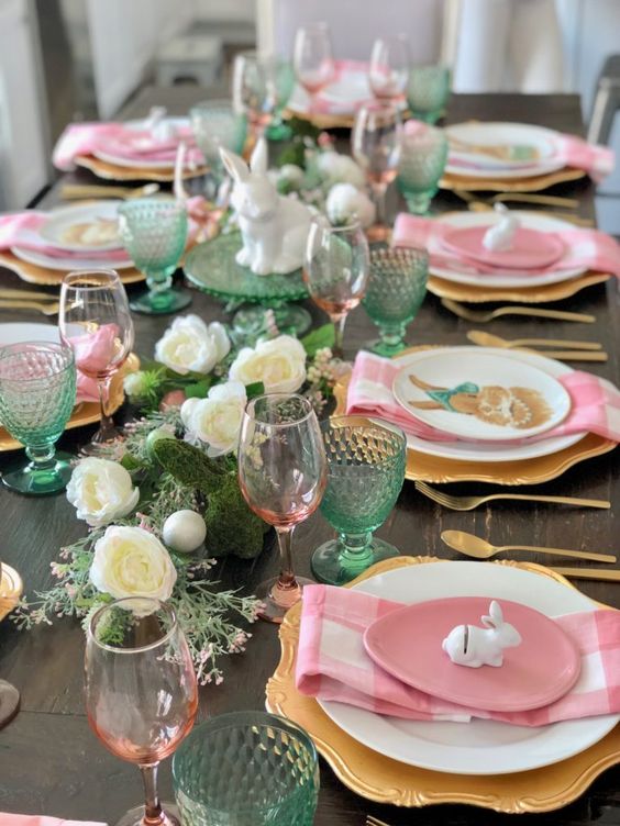 a green and pink Easter tablescape with a greenery and white bloom runner, pink and green glasses, pink plates and napkins
