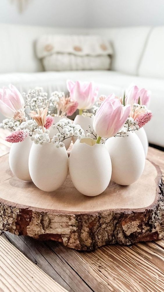 a lovely Easter centerpiece of a tree slice with egg shells as vases with pink and white blooms is amazing