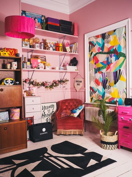 a maximalist kitsch home office in pink, with built in shelves, mid century modern furniture, lots of decor and a bold artwork