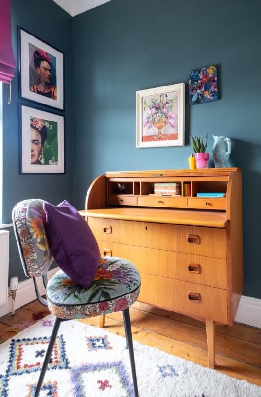 a maximalist working nook with grey walls, a vintage bureau desk, a colorful chair and bold textiles plus a bright gallery wall