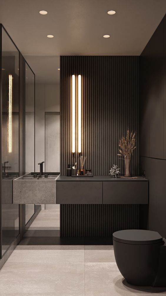 a minimalist black powder room with matte walls and wooden slats, a built in vanity, lights and a mirror