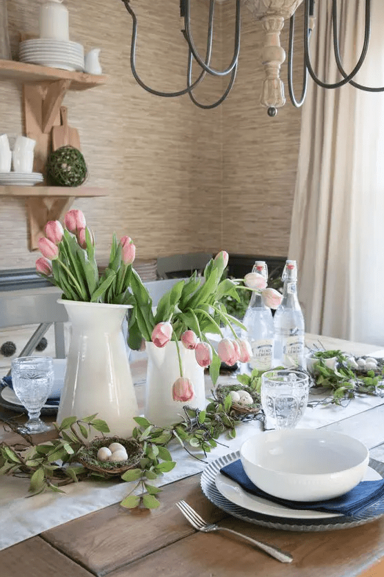 a modern farmhouse Easter table with a neutral runner, navy napkins and white porcelain, pink tulips and nests with eggs