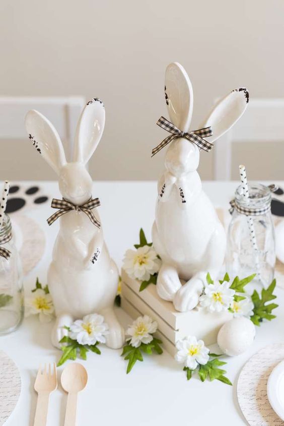 a neutral Easter centerpiece of a crate with white blooms and bunnies with bows is a cool idea for a modern tablescape